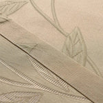 Gros plan sur un tissu beige avec un motif de feuilles en relief, idéal pour un usage décoratif intérieur. Ce détail met en valeur la finesse du design et l'élégance discrète de l'ensemble. Parfait pour ajouter une touche naturelle et sophistiquée à tout espace.