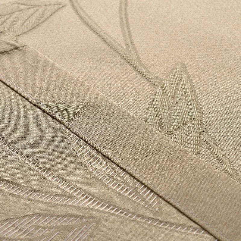 Gros plan sur un tissu beige avec un motif de feuilles en relief, idéal pour un usage décoratif intérieur. Ce détail met en valeur la finesse du design et l'élégance discrète de l'ensemble. Parfait pour ajouter une touche naturelle et sophistiquée à tout espace.