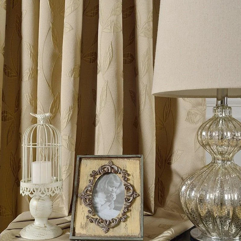 Rideaux élégants avec motif de feuilles en relief, parfaits pour apporter une touche de sophistication à votre intérieur. Complétez la décoration avec une lampe de table au design raffiné, un cadre photo vintage et un photophore décoratif pour une ambiance chaleureuse et accueillante. Idéal pour un salon ou une chambre à coucher.