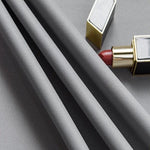 Image d'un tissu gris élégant disposé avec soin à côté d'un rouge à lèvres rouge glamour. Parfaite pour illustrer le raffinement et le style intemporel. Idéale pour les articles de mode et d'accessoires beauté.