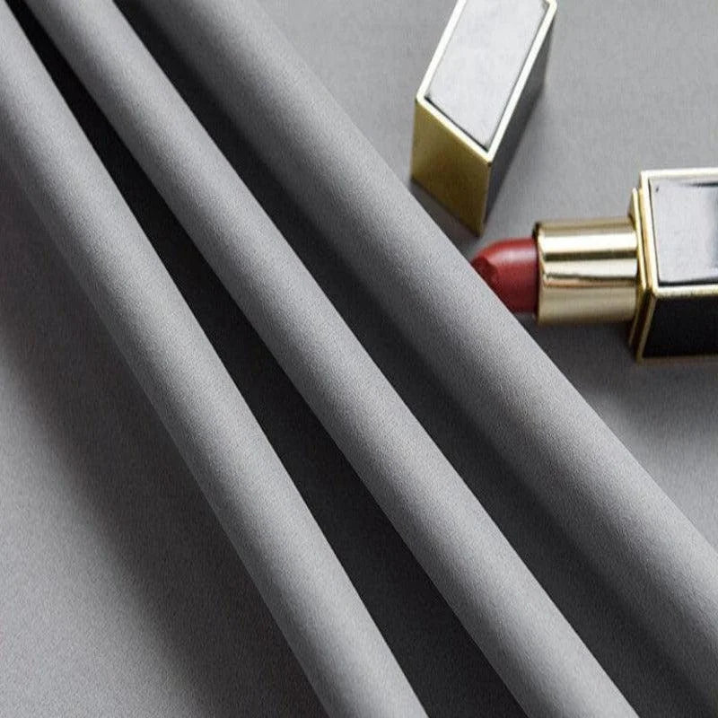 Image d'un tissu gris élégant disposé avec soin à côté d'un rouge à lèvres rouge glamour. Parfaite pour illustrer le raffinement et le style intemporel. Idéale pour les articles de mode et d'accessoires beauté.
