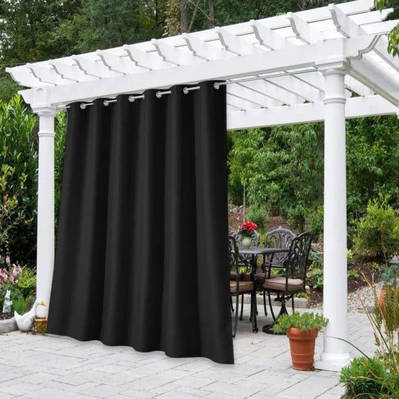 Voilage d'extérieur noir élégant suspendu sous une pergola blanche dans un jardin verdoyant, offrant une ambiance intime et raffinée pour se détendre en plein air. Ajoutez une touche de sophistication à votre espace extérieur avec ces rideaux qui vous protègent du soleil tout en créant une atmosphère chaleureuse. Parfait pour les réunions en famille ou entre amis, avec en arrière-plan un coin salon de jardin accueillant et fleuri.