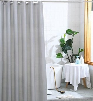 Rideau de douche gris élégant dans une salle de bain moderne, décoré avec des éléments naturels. Ce rideau pratique et esthétique offre une solution idéale pour préserver l'intimité tout en ajoutant une touche de sophistication à votre espace. Parfait pour les salles de bain contemporaines à la recherche d'une ambiance épurée.