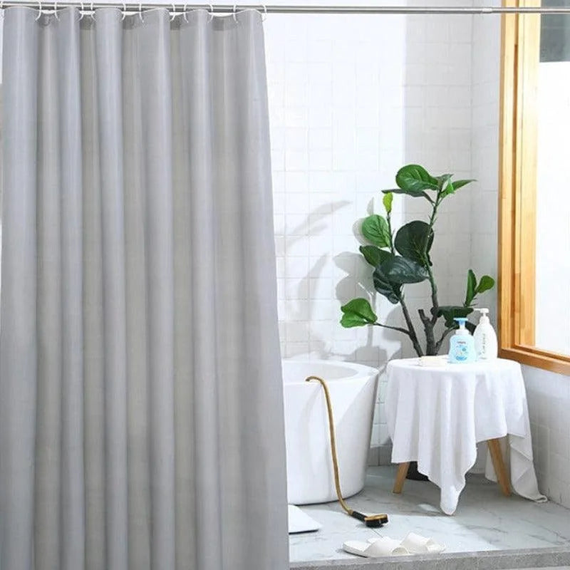Rideau de douche gris élégant dans une salle de bain moderne, décoré avec des éléments naturels. Ce rideau pratique et esthétique offre une solution idéale pour préserver l'intimité tout en ajoutant une touche de sophistication à votre espace. Parfait pour les salles de bain contemporaines à la recherche d'une ambiance épurée.