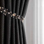 Rideau élégant noir avec motif géométrique, maintenu par un embrasse décoratif en forme de branche florale ornée de perles et de cristaux, ajoutant une touche raffinée et sophistiquée à tout intérieur moderne. Idéal pour salon ou chambre à coucher.