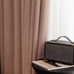 Rideaux élégants de couleur taupe, ajoutant une touche de sophistication à tout intérieur. À droite, une enceinte vintage repose sur une table sombre, accompagnée d'un livre, créant une ambiance cosy et moderne parfaite pour un salon ou une chambre.