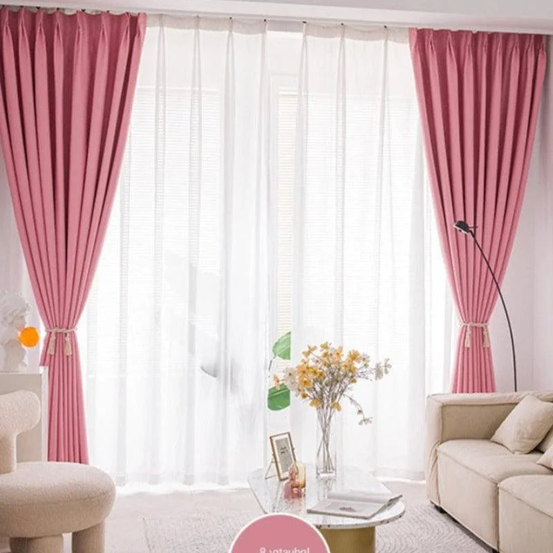 Rideaux élégants de couleur rose installés dans un salon moderne, offrant une ambiance lumineuse et chaleureuse grâce à la combinaison de voilages blancs. Complétant le décor, un canapé confortable et une table basse ornée de fleurs jaunes ajoutent une touche de sophistication et de confort à l'intérieur. Parfait pour créer un espace accueillant et stylé.