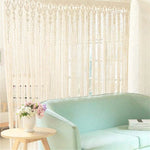 Rideau décoratif beige, parfait pour créer une ambiance lumineuse et accueillante dans le salon. Ce rideau ajouré s'accorde harmonieusement avec un canapé vert menthe et un intérieur moderne. Élément idéal pour ajouter une touche élégante et bohème à votre décoration d'intérieur.