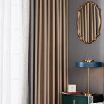 Rideau élégant couleur taupe pour salon moderne, accompagné d'un miroir doré au mur et d'une lampe de chevet bleue, parfaite pour une décoration intérieure raffinée et contemporaine. Idéal pour créer une ambiance chaleureuse et sophistiquée dans votre espace de vie.