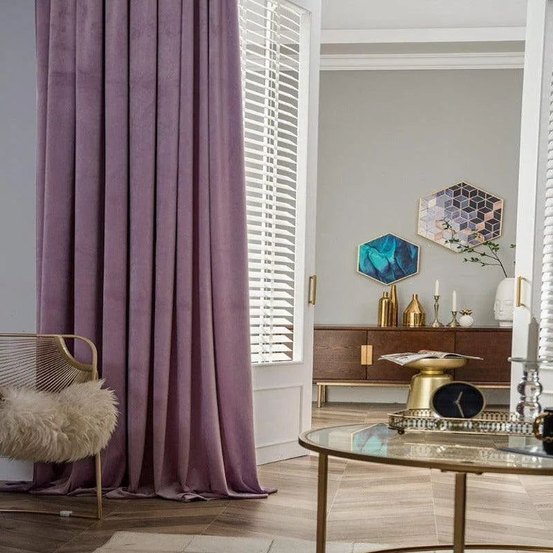 Rideau violet élégant et moderne dans un salon raffiné, décoré avec un mobilier en bois foncé et des éléments dorés, accentuant un design intérieur contemporain et chaleureux. Les murs gris clairs et les œuvres d'art géométriques ajoutent une touche de sophistication à l'ensemble. Un fauteuil avec un coussin moelleux complète l'ambiance accueillante de la pièce.