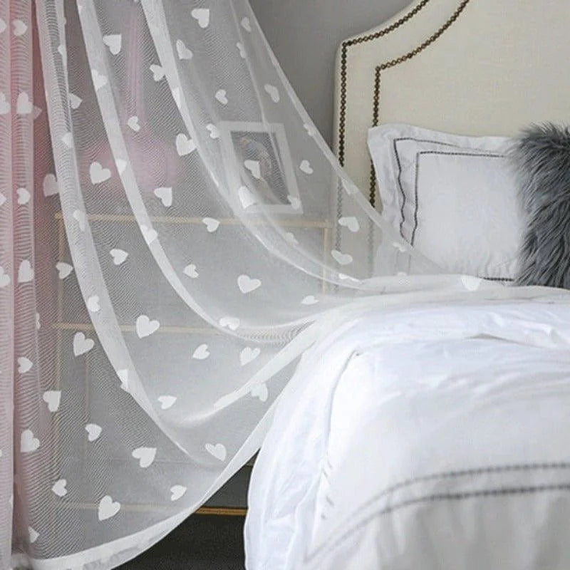 Voilage décoratif à motifs de cœurs blanc, idéal pour une chambre à coucher élégante. Ce rideau ajoute une touche romantique et subtilement moderne à votre intérieur. Accompagne parfaitement une literie claire et des oreillers stylés pour un effet apaisant.