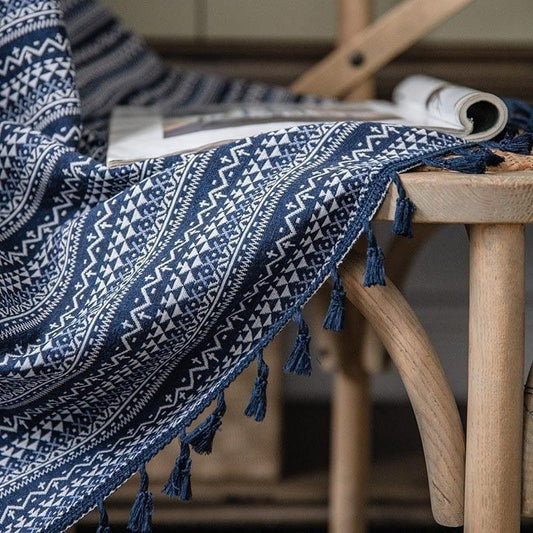 Plaid bleu à motifs géométriques sur une chaise en bois, avec franges décoratives, idéal pour une décoration intérieure cosy et chaleureuse. Ce textile ajoute une touche élégante et moderne à tout salon ou chambre à coucher. Parfait pour se draper lors des soirées fraîches.