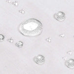 Gouttes d'eau sur un tissu blanc, illustrant l'effet déperlant efficace et moderne, idéal pour une protection contre l'humidité et les liquides. Solution parfaite pour les environnements nécessitant une surface facile à entretenir tout en garantissant un aspect propre et net.