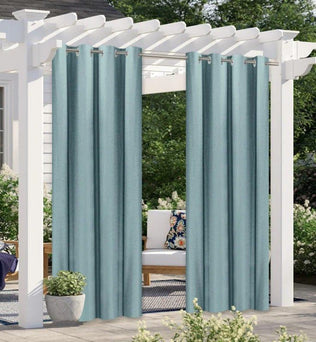 Rideaux d'extérieur bleus suspendus à une pergola blanche dans un jardin, offrant une ambiance élégante et intime pour les espaces extérieurs.