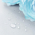 Image montrant des gouttes d'eau sur une surface imperméable, illustrant l'efficacité du produit en termes de résistance à l'humidité. Fleur bleue en arrière-plan ajoutant une touche esthétique. Idéal pour démontrer la fonctionnalité et l'élégance du produit dans un cadre domestique.