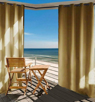 Rideaux occultants beige pour terrasse avec vue sur la mer, offrant une protection solaire optimale et créant une ambiance extérieure élégante. Aménagement de balcon avec mobilier en bois pour un espace détente confortable au bord de l'eau.