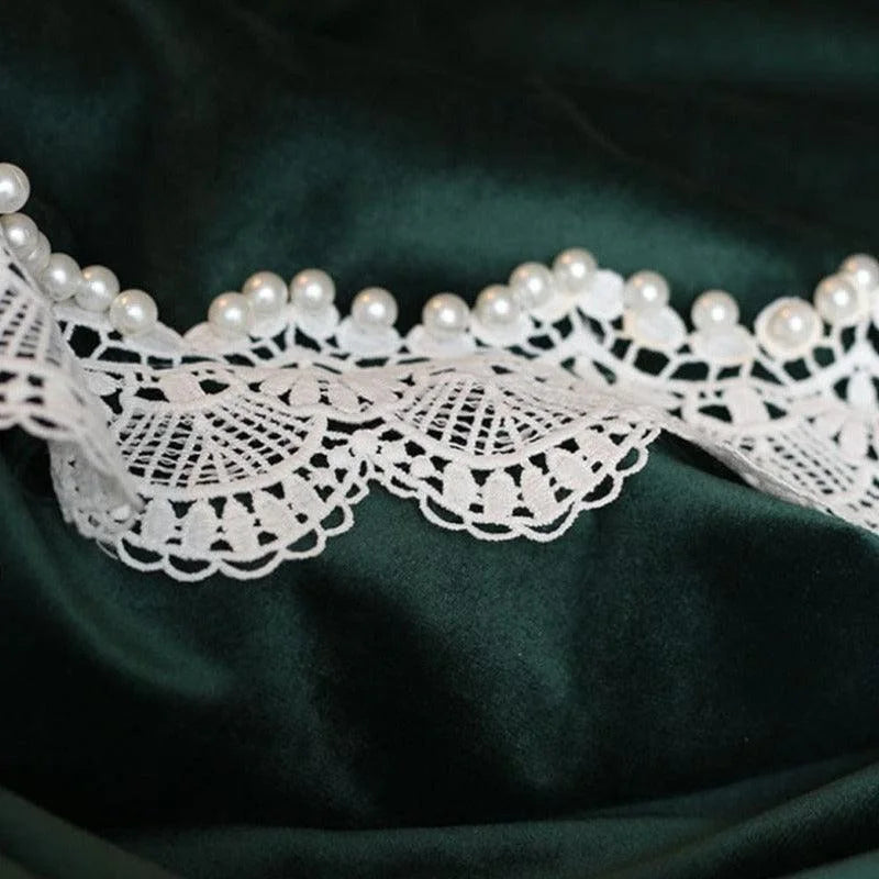 Dentelle décorative blanche avec perles, posée sur un fond sombre, parfaite pour la couture et la décoration de vêtements, idéale pour un look élégant et raffiné. Accessoire de mode indispensable pour personnaliser vos créations vestimentaires.