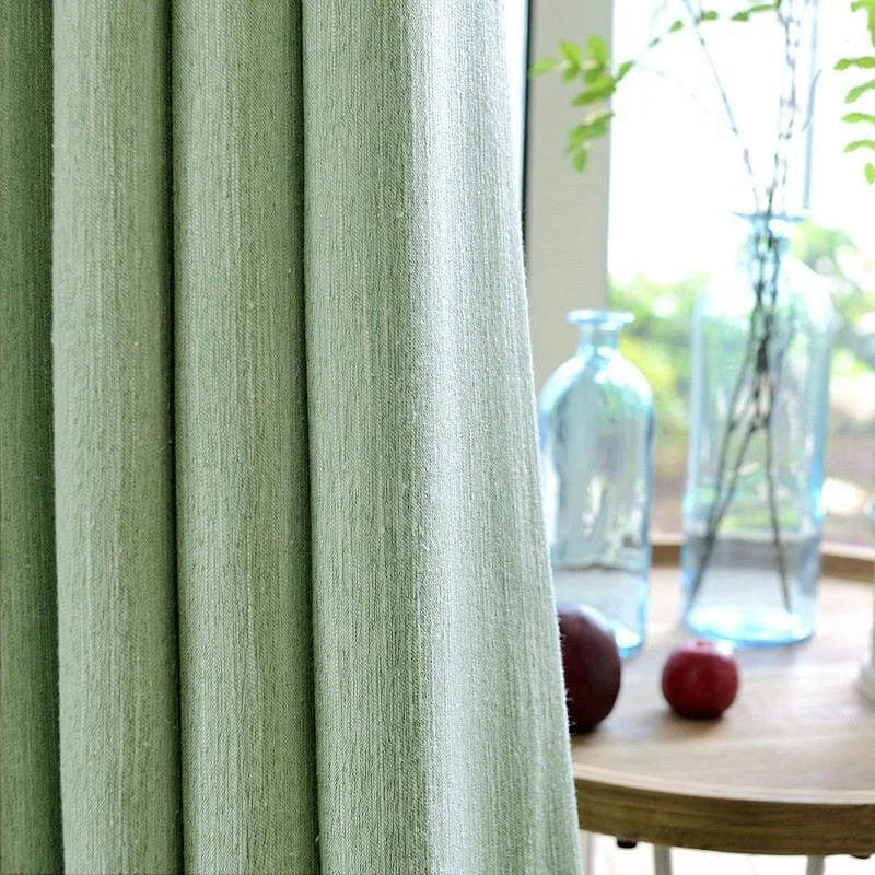 Rideau vert pastel élégant dans un intérieur lumineux avec des bouteilles décoratives en verre et des éléments naturels, parfait pour une ambiance sereine et moderne.
