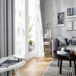 Salon moderne et élégant avec canapé confortable, table basse design et tapis à motifs géométriques. Intérieur lumineux et accueillant, idéal pour un espace de vie harmonieux. Fenêtres avec rideaux élégants et décoration murale contemporaine. Ambiance agréable avec éclairage naturel.
