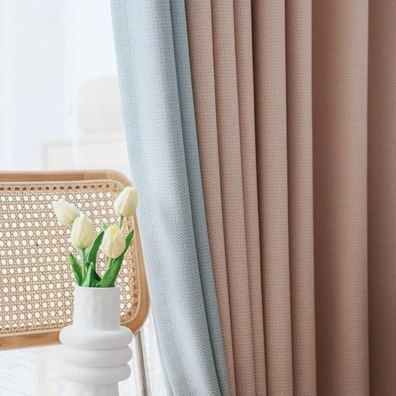 Rideaux élégants aux tons beige et bleu pastel, ajoutant une touche sophistiquée à votre intérieur. Parfaits pour une décoration moderne, ces rideaux s'harmonisent avec un mobilier en bois clair. Vase blanc avec tulipes pour un accent naturel dans votre salle de séjour. Idéal pour créer une ambiance accueillante et lumineuse.