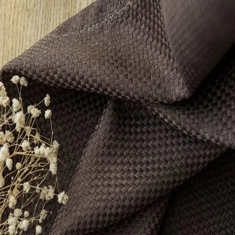 Tissu marron tissé pour décoration intérieure, élégant et raffiné, idéal pour les rideaux ou revêtements de meubles, parfait pour ajouter une touche chaleureuse à votre espace de vie. Arrière-plan en bois clair et touche de fleurs séchées.