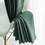 Plaid vert foncé drapé sur une chaise moderne, ajoutant une touche élégante à la décoration intérieure. Ce plaid est idéal pour apporter chaleur et style à votre salon ou chambre à coucher. Son design raffiné s'intègre parfaitement dans un cadre contemporain. Parfait pour se détendre lors des soirées fraîches.