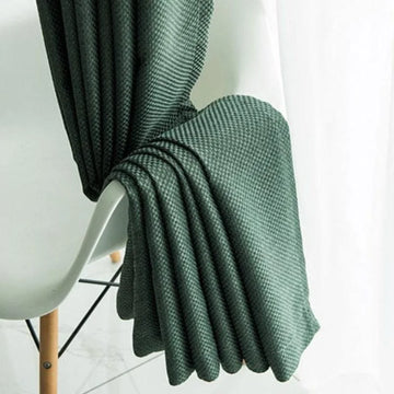 Plaid vert foncé drapé sur une chaise moderne, ajoutant une touche élégante à la décoration intérieure. Ce plaid est idéal pour apporter chaleur et style à votre salon ou chambre à coucher. Son design raffiné s'intègre parfaitement dans un cadre contemporain. Parfait pour se détendre lors des soirées fraîches.