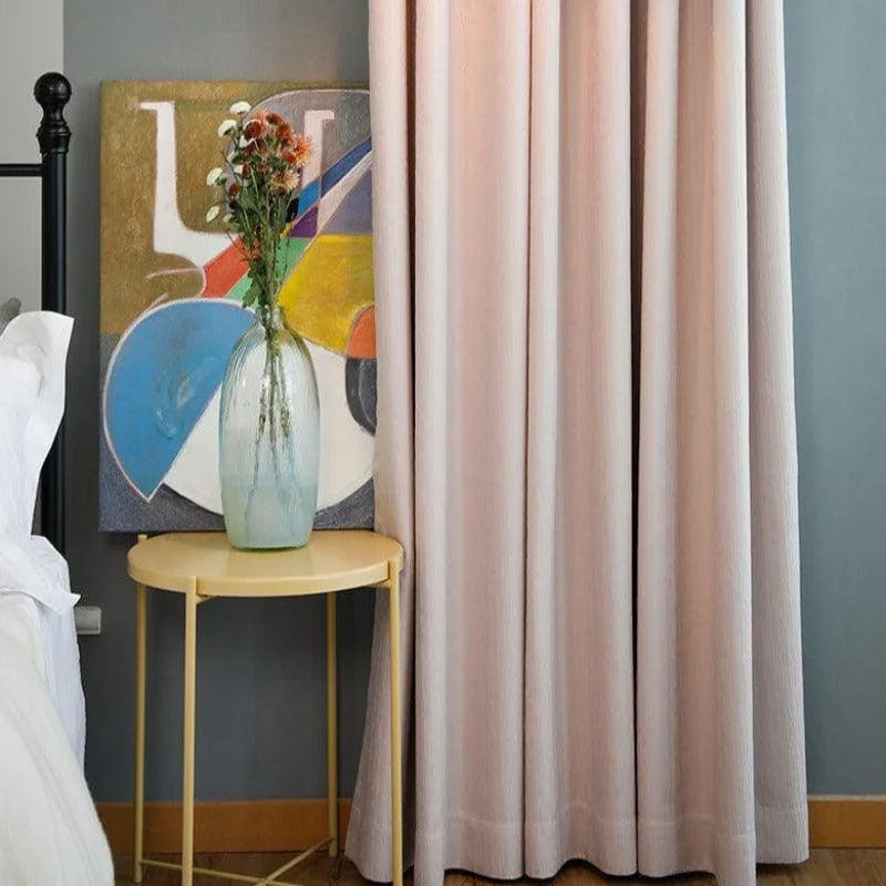 Rideau élégant de couleur beige dans un intérieur moderne, créant une ambiance chaleureuse. À côté, une petite table ronde jaune supporte un vase décoratif transparent avec des fleurs séchées, apportant une touche artistique et naturelle à la pièce. Le tout est harmonieusement complété par un tableau aux couleurs vives qui ajoute du dynamisme à l'espace.