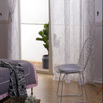 Chambre élégante avec chaise design, décorée de rideaux à motifs et plante d'intérieur, offrant une ambiance moderne et apaisante. Idéale pour aménager un espace de détente à la maison.