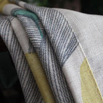Gros plan sur un tissu élégant aux motifs géométriques rayés et aux touches de couleur vibrantes. Accessoire décoratif idéal pour sublimer votre intérieur avec une touche moderne et artistique. Parfait pour un salon ou une salle à manger, ce tissu apporte style et caractère à votre espace.