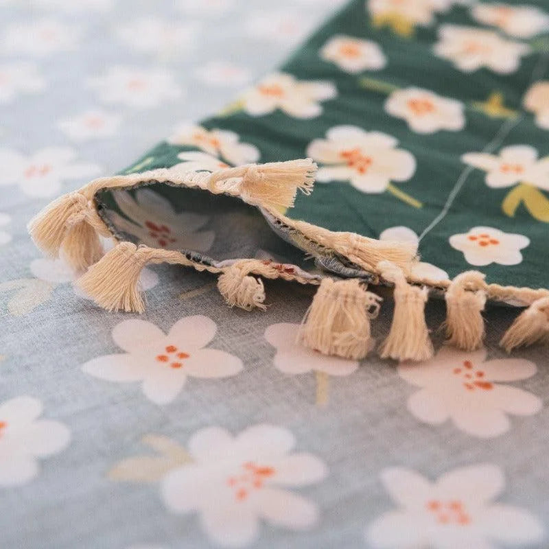 Tissu décoratif à motifs floraux, idéal pour ajouter une touche d'élégance et de couleur à votre intérieur. Ce produit arbore de délicates fleurs blanches sur fond vert, soulignées par des franges qui apportent du charme et de la texture à votre décoration. Parfait pour les projets de couture et d'embellissement de la maison.