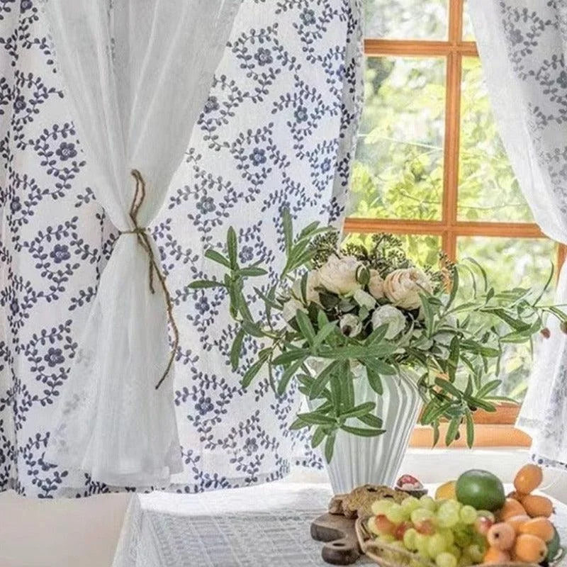 Rideau décoratif avec motifs floraux bleus, idéal pour apporter une touche romantique et élégante à votre salon. Parfait pour encadrer une vue lumineuse et naturelle, ce rideau ajoute une ambiance fraîche à votre intérieur. Idéal pour harmoniser avec des éléments de décoration naturels comme des plantes ou des bouquets de fleurs.