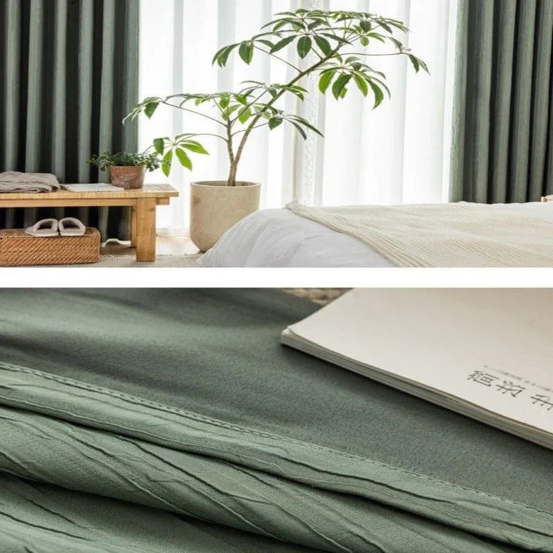 Ensemble de literie élégant et naturel pour une chambre moderne, comprenant une étoffe dans les tons verts doux. L'intérieur est agrémenté d'une plante d'intérieur en pot, apportant une touche de verdure et de tranquillité. Le décor inclut également un banc en bois avec des rangements, parfait pour optimiser l'espace tout en ajoutant du style. Un livre reposant sur le tissu suggère une atmosphère détendue et harmonieuse, idéale pour la lecture et le repos