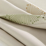 Image d'un tissu beige avec un motif élégant de fleurs stylisées vertes et dorées, idéal pour la décoration intérieure moderne. Ce design apporte une touche de nature et de sophistication à tout espace, s'intégrant parfaitement dans un salon ou une chambre. Tissu polyvalent pour rideaux, coussins ou meubles.