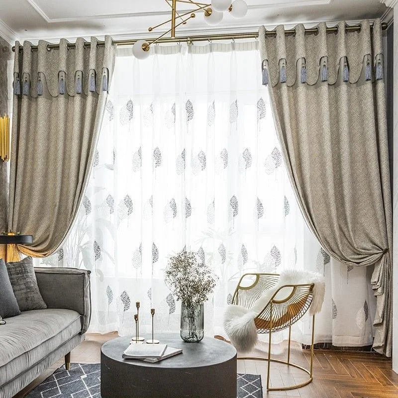 Chambre élégante avec rideaux opaques gris et voilage à motifs, apportant une ambiance chaleureuse et moderne. Complètement intégrés dans un salon chic avec un canapé gris, un fauteuil design et une table basse noire, ces rideaux améliorent l'esthétique de l'espace. Leur suspension en anneaux ajoute une touche de sophistication. Parfait pour une décoration intérieure contemporaine et tendance.