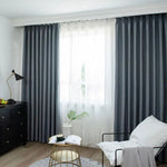 Rideaux occultants gris élégants dans un salon moderne avec lumière naturelle, mobilier contemporain et décoration minimaliste pour un intérieur chic et fonctionnel.