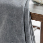 Couverture grise élégante sur table en bois, idéale pour décorer le salon ou la chambre, apportant une touche de confort et de style à votre intérieur. Accessoire intemporel pour un design moderne.