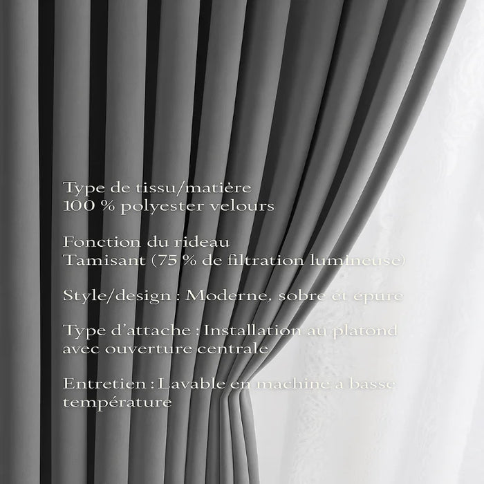 Gros plan sur un rideau en velours gris clair, plissé, installé devant une fenêtre avec un voilage blanc en arrière-plan.