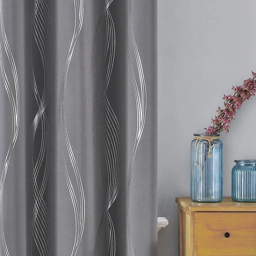 Rideau moderne gris avec motifs ondulés blancs, idéal pour embellir un salon ou une chambre à coucher. Ce rideau élégant ajoute une touche contemporaine à votre décoration intérieure. À côté, un meuble en bois clair est décoré de deux vases bleus et d'une branche fleurie, offrant un contraste visuel attrayant et harmonieux. Parfait pour une ambiance cosy et sophistiquée.