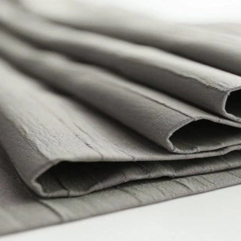 Image de gros plan d'un tissu de couleur grise, montrant un effet texturé et souple, idéal pour la décoration intérieure moderne ou la confection de vêtements élégants. Ce tissu apporte une touche sophistiquée à tous vos projets de couture.