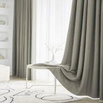 Rideaux élégants gris dans un salon moderne, accentuant une décoration intérieure minimaliste avec un tapis graphique et une table blanche. Ambiance lumineuse et sereine pour un espace de vie contemporain.