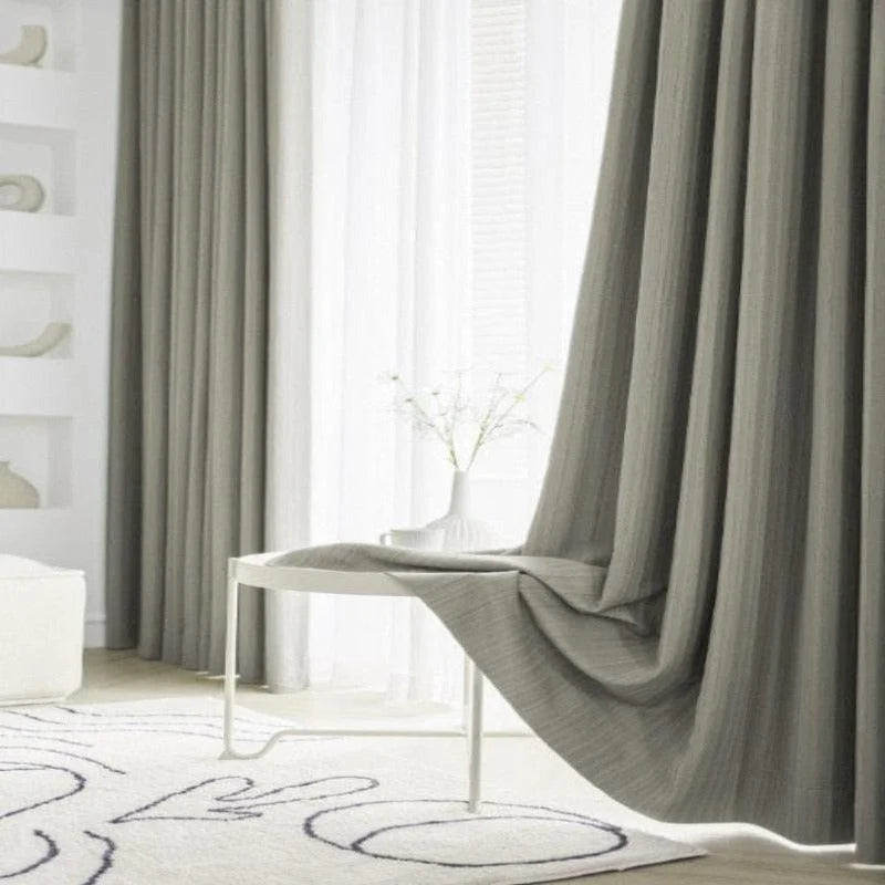Rideaux élégants gris dans un salon moderne, accentuant une décoration intérieure minimaliste avec un tapis graphique et une table blanche. Ambiance lumineuse et sereine pour un espace de vie contemporain.