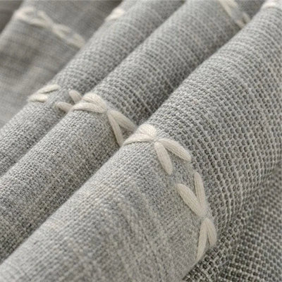Textile décoratif gris avec motifs brodés en relief, style élégant et moderne, idéal pour la maison.