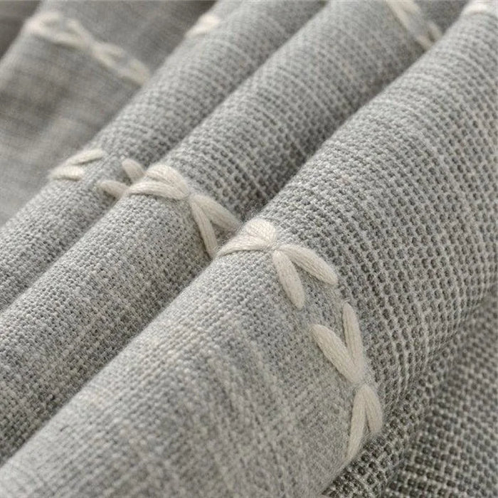 Textile décoratif gris avec motifs brodés en relief, style élégant et moderne, idéal pour la maison.