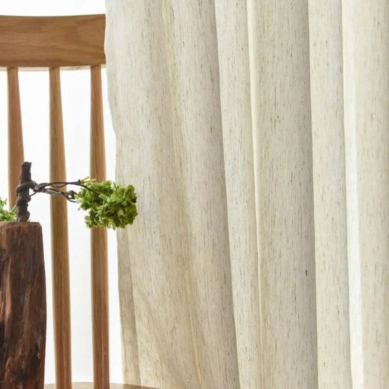 Chaises en bois élégantes avec rideaux légers pour une ambiance naturelle et apaisante dans le salon. Décoration sobre intégrant un vase original, idéal pour un intérieur moderne et chaleureux.