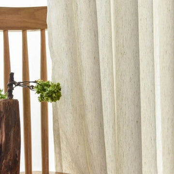 Chaises en bois élégantes avec rideaux légers pour une ambiance naturelle et apaisante dans le salon. Décoration sobre intégrant un vase original, idéal pour un intérieur moderne et chaleureux.