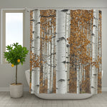 Rideau de douche imprimé forêt de bouleaux avec feuillage automnal doré, installé dans une salle de bain lumineuse avec une plante en pot à gauche.