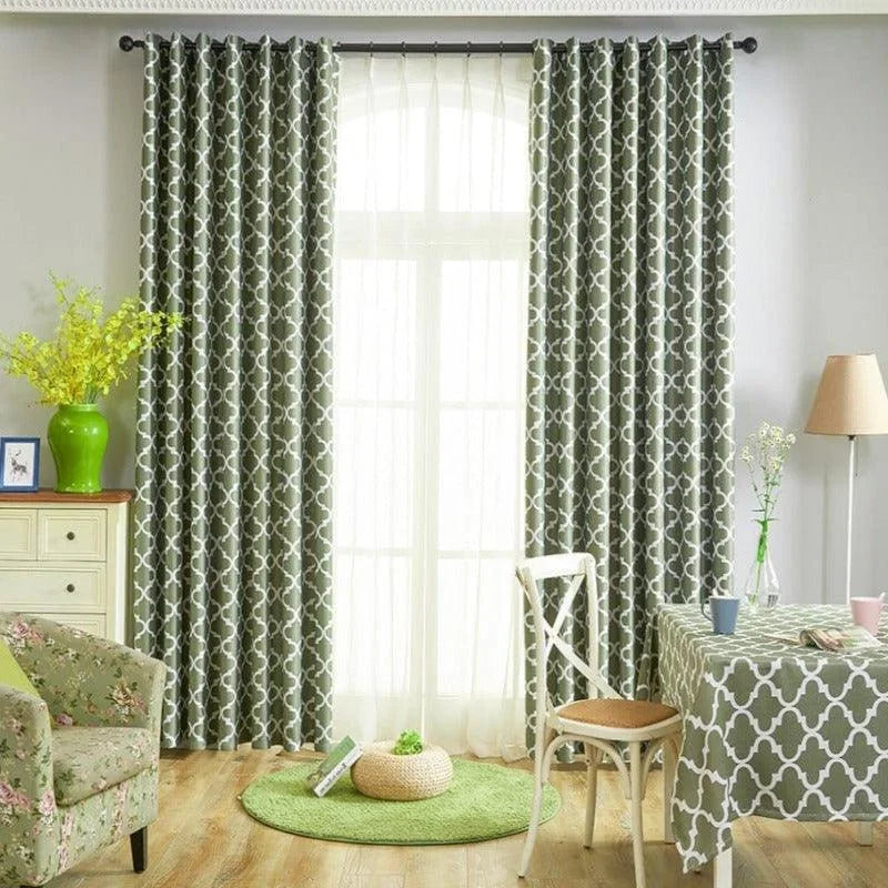 Rideaux à motifs géométriques modernes pour salon, ornant une fenêtre lumineuse. Décoration élégante combinée avec des meubles assortis, comme une table recouverte d'une nappe et un fauteuil aux motifs floraux, pour un intérieur harmonieux et accueillant. Ambiance lumineuse et contemporaine.