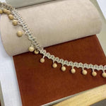 Deux échantillons de tissu, un beige et un marron, sont présentés avec une garniture à pompons décoratifs. Parfait pour une décoration intérieure élégante et chaleureuse.