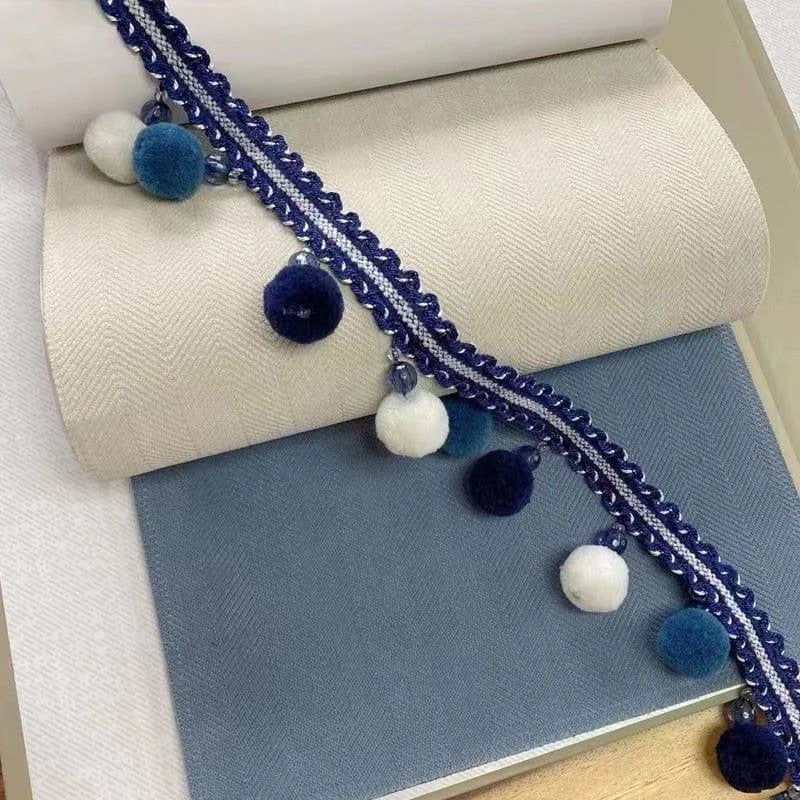 Garniture décorative bleu et blanche avec pompons et perles, parfaite pour embellir vos projets de couture et d'artisanat. L'accessoire idéal pour ajouter une touche élégante et personnalisée à vos créations.
